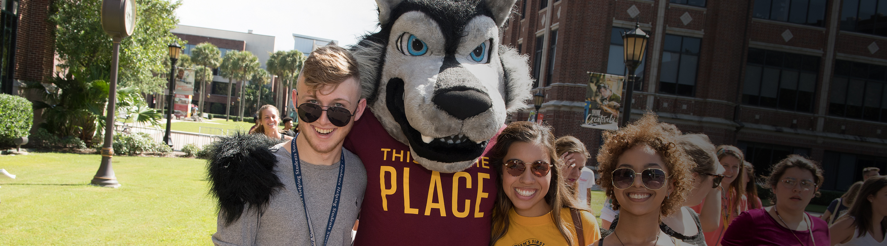 Group of smiling students with wolf mascot Havoc