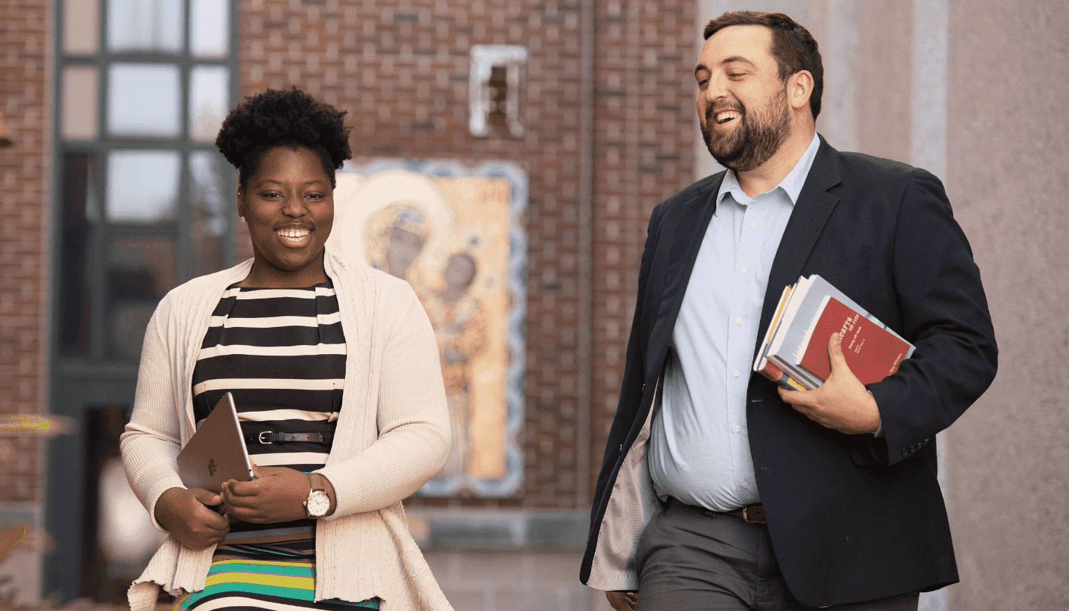 Two online Loyola students having a discussion as they walk across campus.