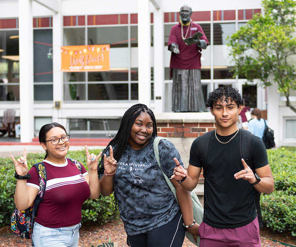 A trio of students make the "sign of the pack" near the Iggy statue.