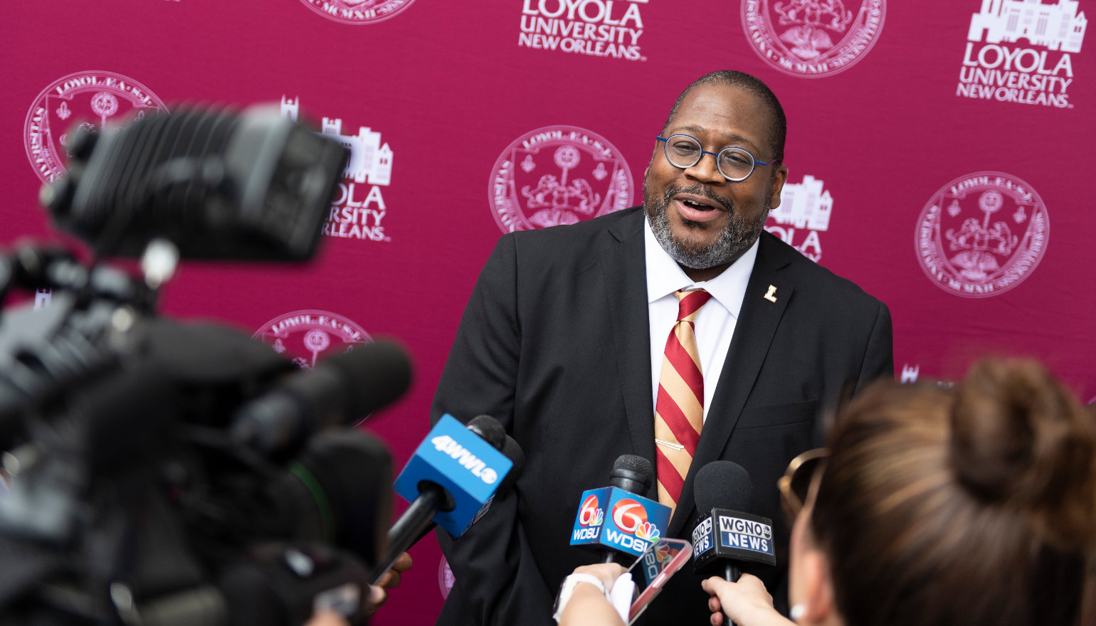 A crowd of reporters surround Dr. Cole in front of a Loyola backdrop.