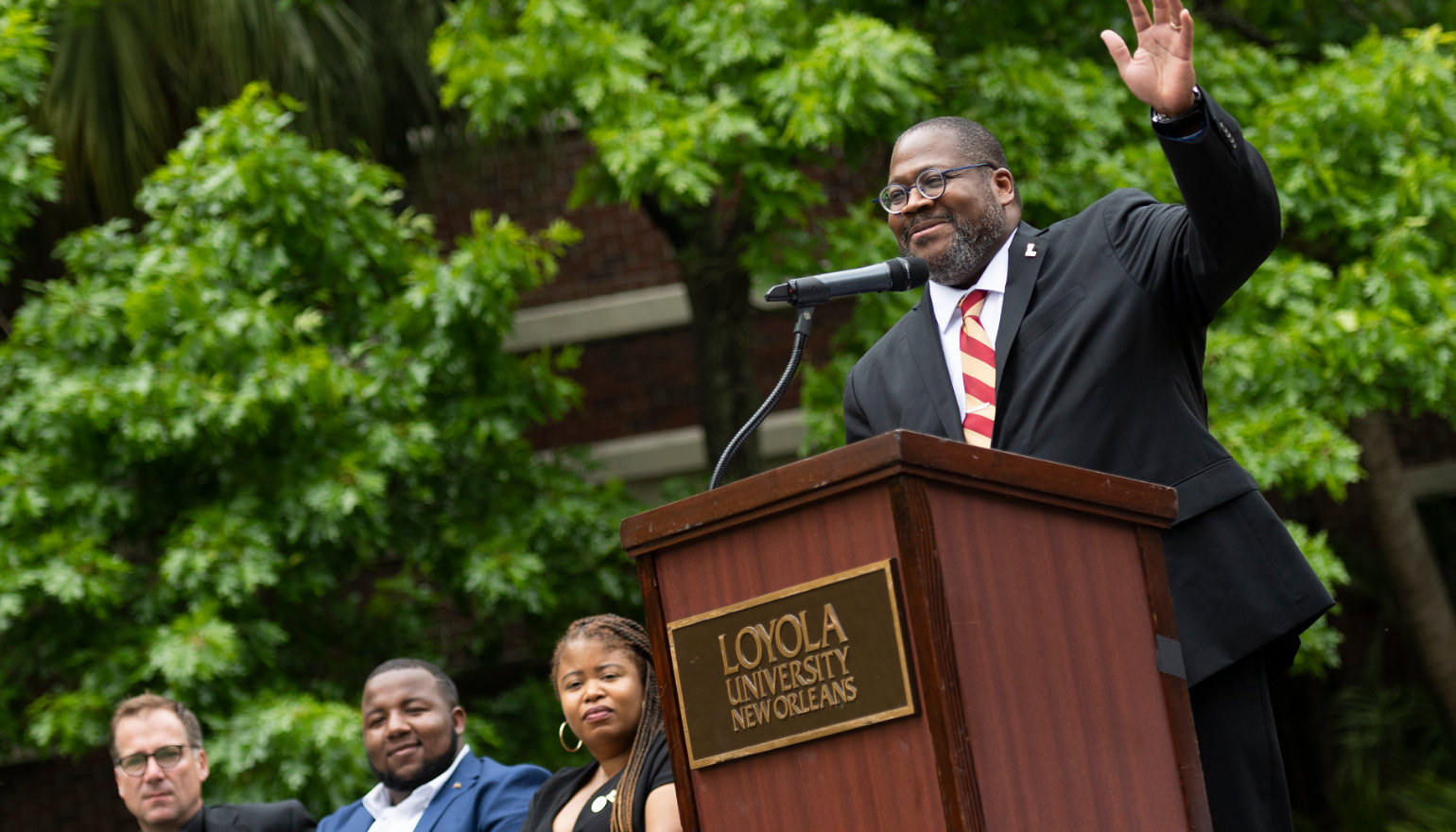 Xavier Cole raises his hand as he speaks at the podium