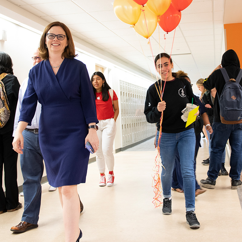 Rana and President Tetlow walk through hallway with balloons